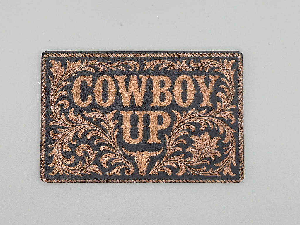 Decorative hat patch with 'Cowboy Up' text and decorative border on a black background.